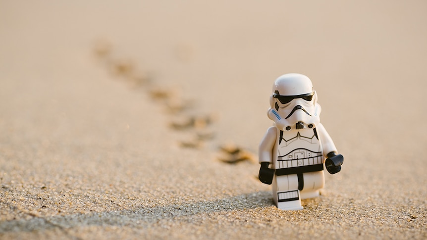 A storm trooper figurine photographed to look like it's walking through the sand.
