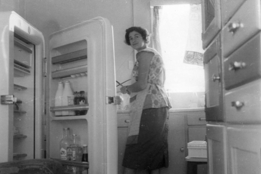 Açık kapı buzdolabı ile 1950'lerin mutfağından kadın.
