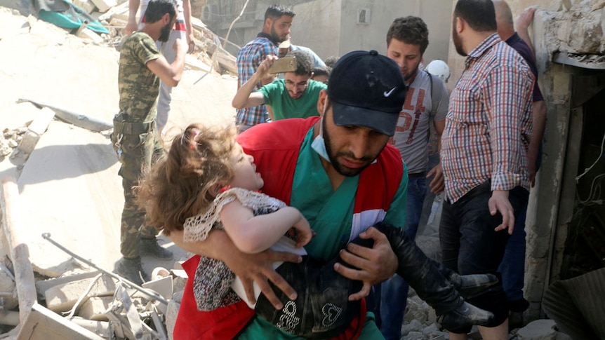 A man carries a child that survived from under the rubble.
