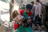 A man carries a child that survived from under the rubble.