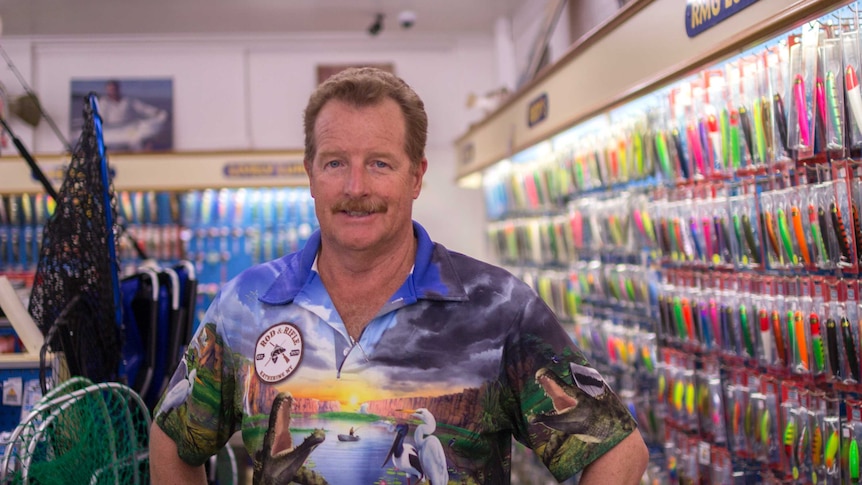 a man in a bight shirt in a fishing shop.