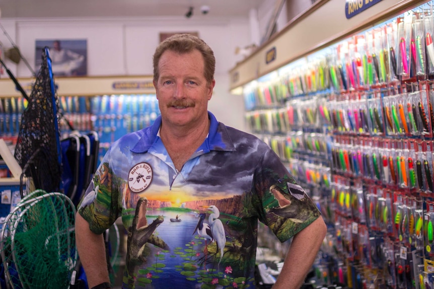 a man in a bight shirt in a fishing shop.