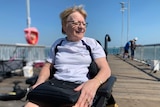 Robyn Burridge is in a wheelchair on a jetty. She is smiling at the sea.