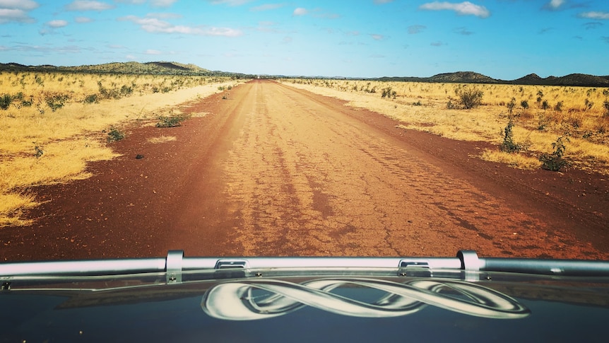 View of an open road from a car with ABC logo on bonnet.