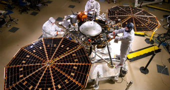 Mars InSight lander surrounded by workers in NASA headquarters from birds-eye view.