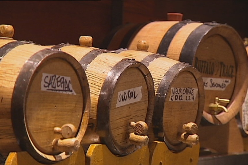 Barrels of whiskey are stacked on top of each other in a distllery.