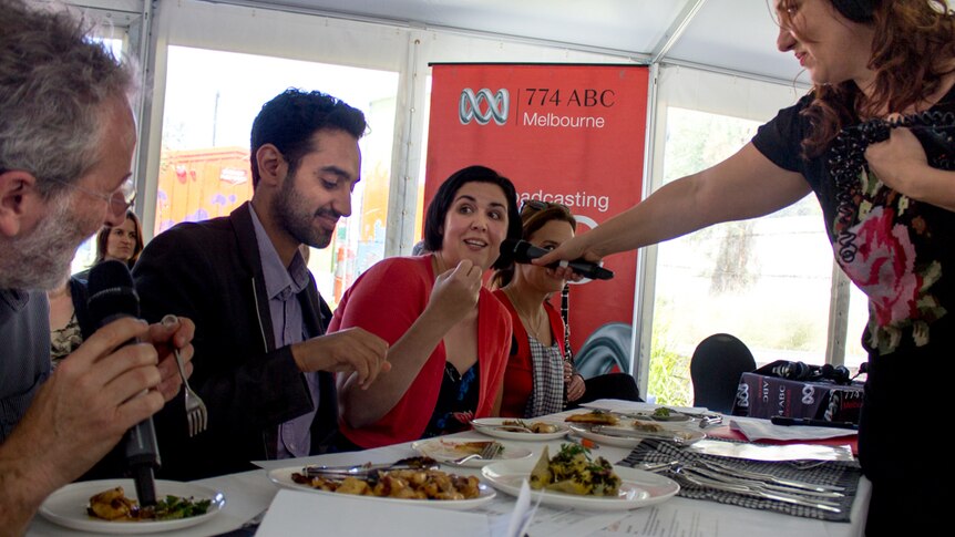 People talk into microphones while eating food.