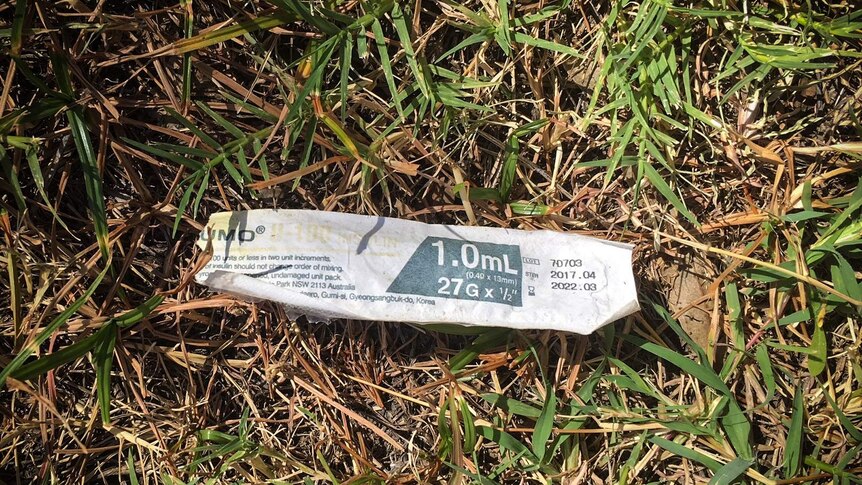 A needles packet disposed on the grass.
