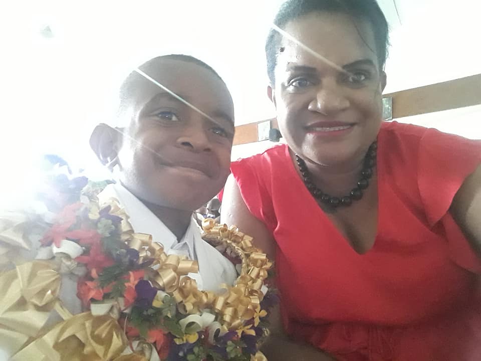 A Fijian woman and her young son smile.