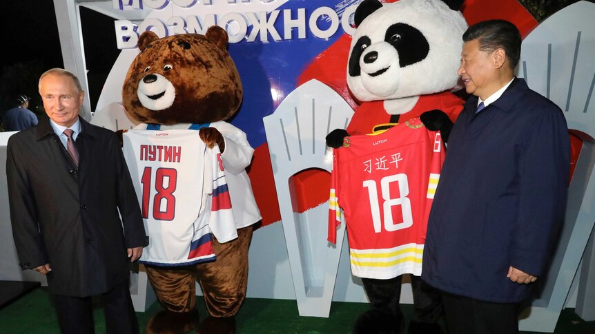 Russian president Vladimir Putin and Xi Jinping stand with bears carrying hockey jerseys