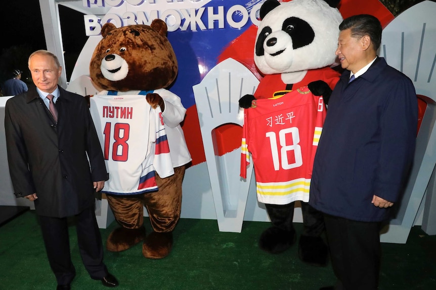 Russian president Vladimir Putin and Xi Jinping stand with bears carrying hockey jerseys
