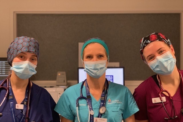 Three women in medical uniforms wearing patterned scrub caps.