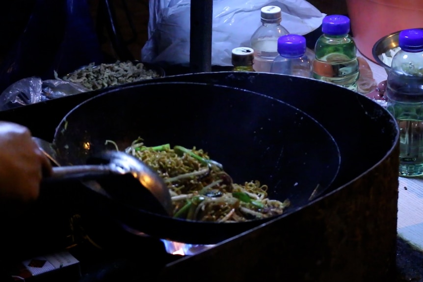 A photo of noodles being cooked in a wok-style pot. 