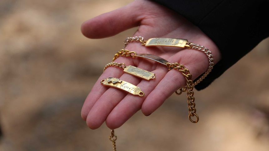 A gold bracelet in the palm of a woman's hand.