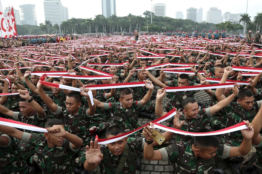 Indonesian soldiers hold up headbands in the colour of the national flag during a rally.