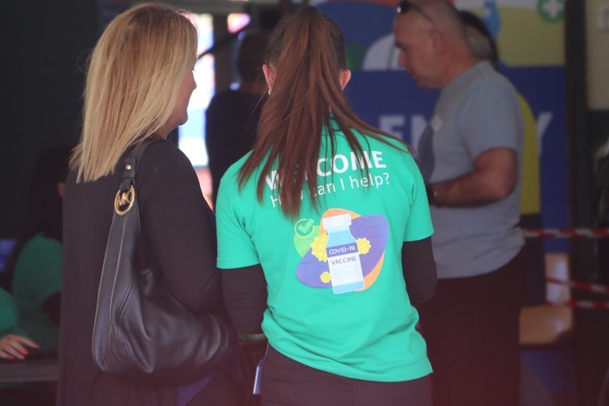 A worker helps a woman at the Rocklea Showgrounds.