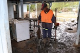 a man cleaning up inside a house after floodwater damage