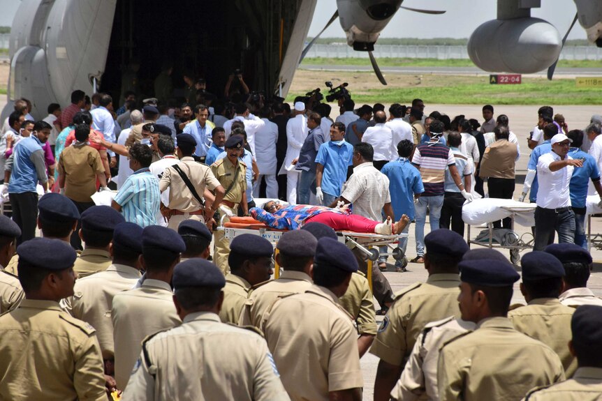 A woman on a stretcher is taken towards a military plane.