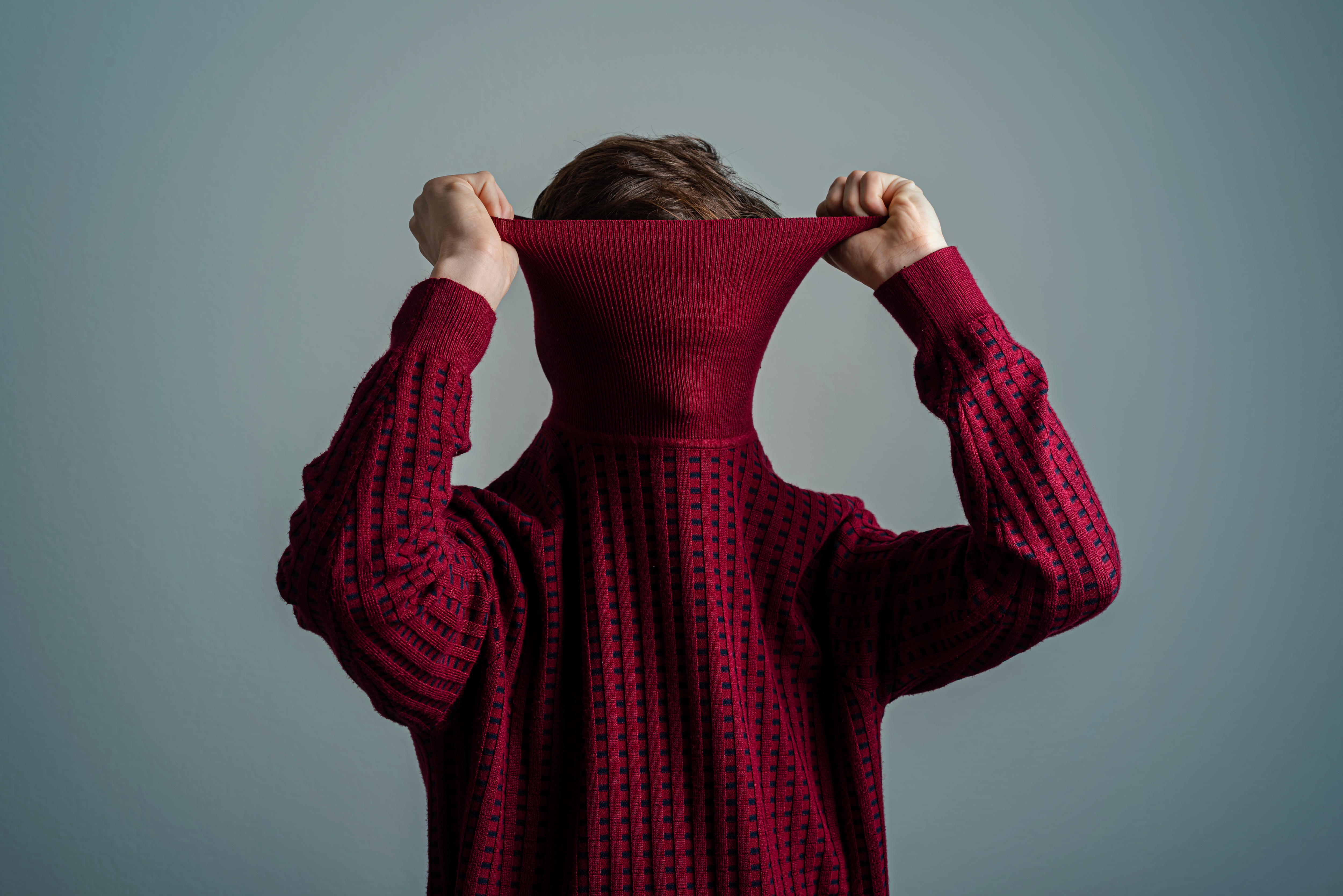 Image of someone pulling their jumper up to cover their head.