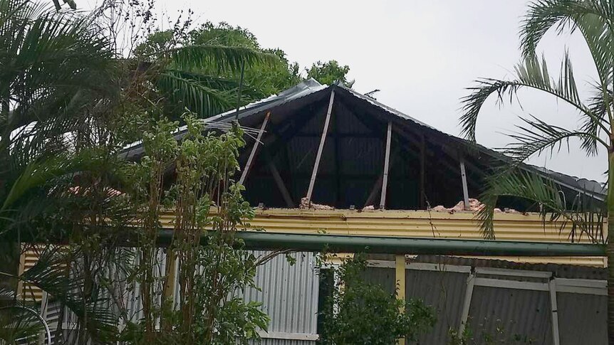 A home with a badly damaged roof and smashed windows