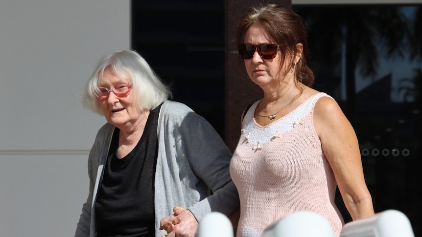 Two ladies holding hands and leaving the court house in Darwin.