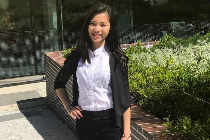 A young Vietnamese woman stands and smiles at the camera.