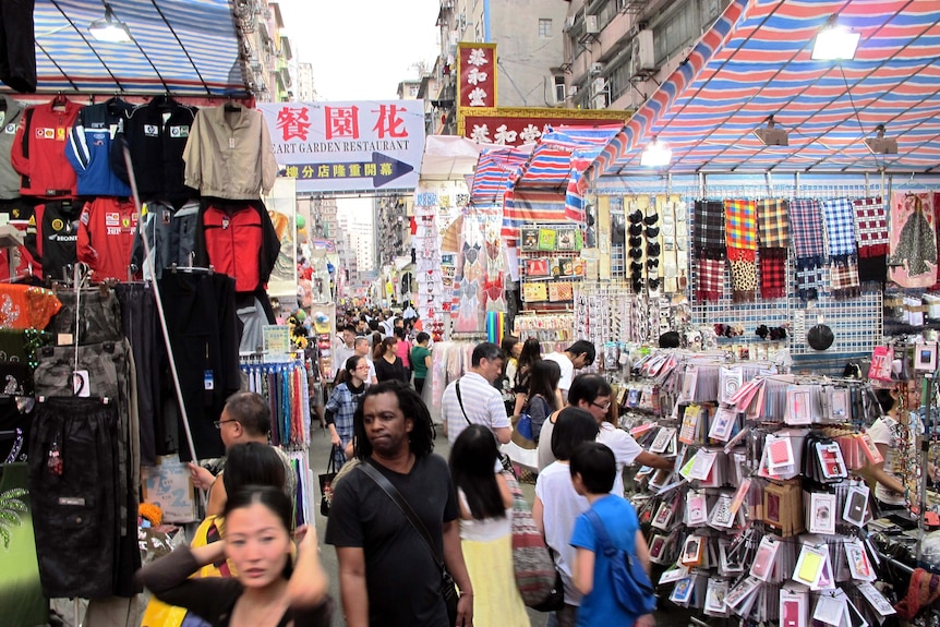 People walk through a busy market place in Mong Kok