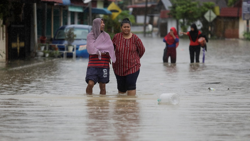 People wade through a flooded residential area at Yong Peng, Johor, Malaysia.