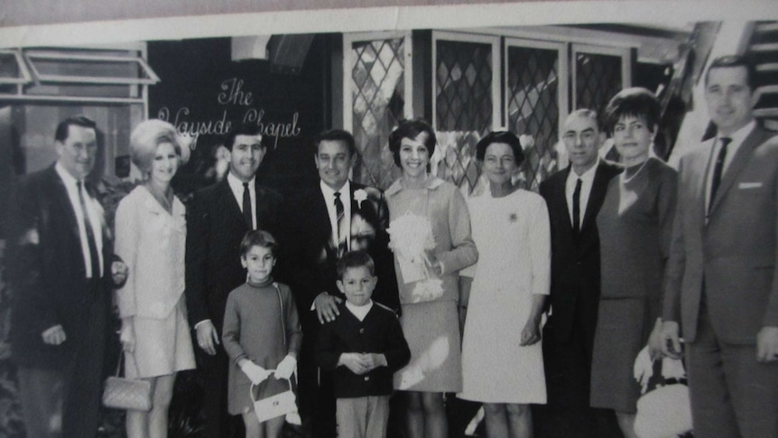 A black and white image of a wedding party posing for the camera.