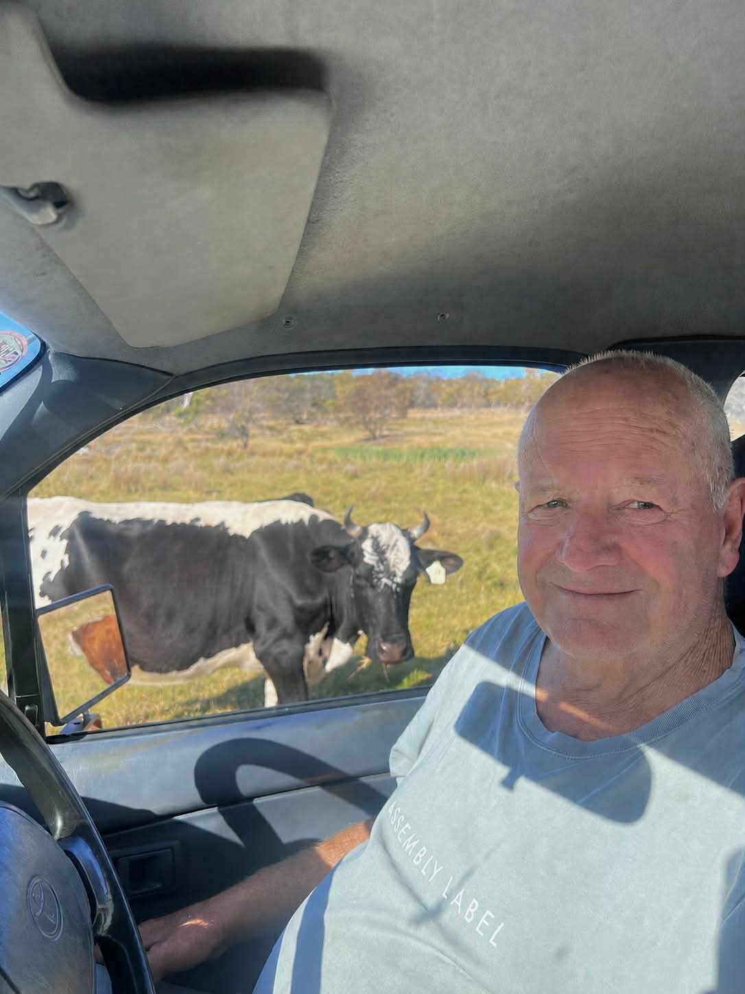 Man smiles at camera with cows in back ground