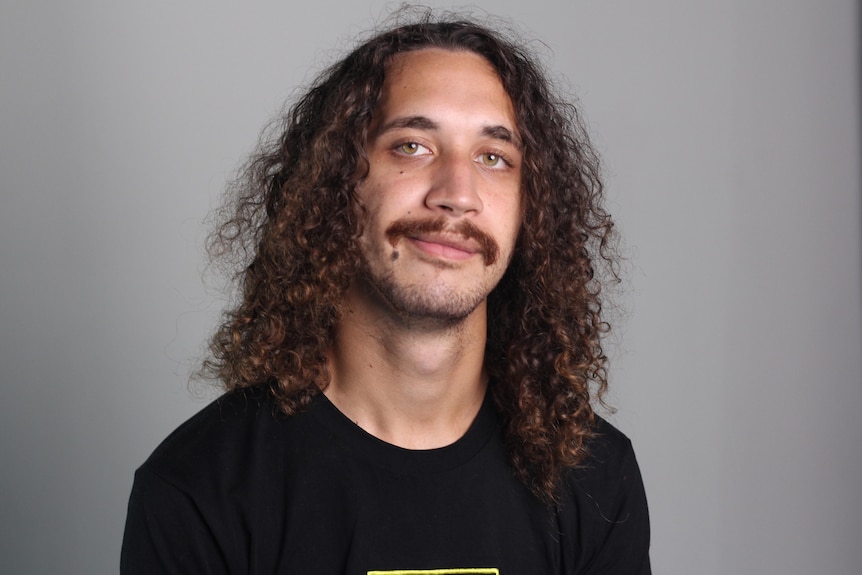 Young man with long curly brown hair and moustache