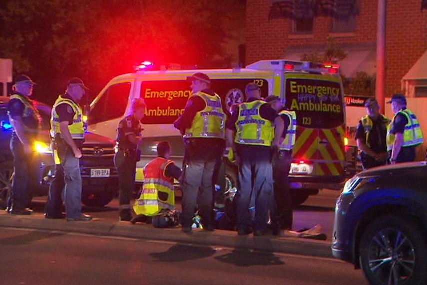Police and paramedics surrounding an ambulance at night