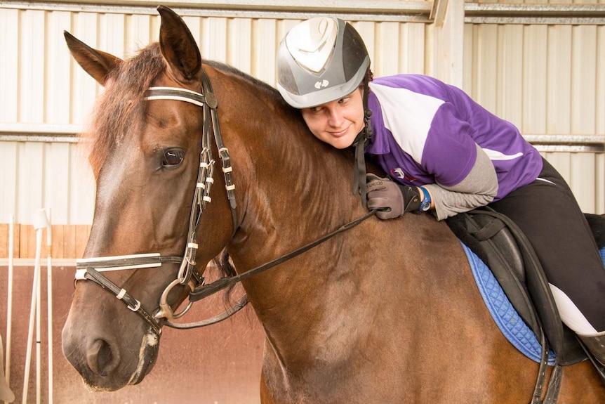 Danyele Foster leans forward in the saddle to embrace the horse she trains with, Bengala.