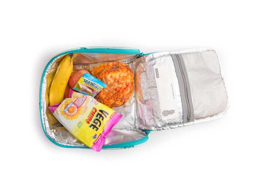 A ham pizza roll, veggie chips, banana, lollies and an apple in a turquoise cooler bag.