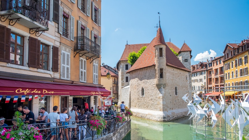 Streetscape of French town of Annecy with river flowing through it.