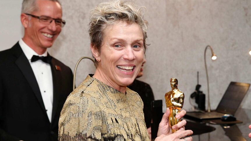 Frances McDormand smiles while holding her Oscar with both hands.