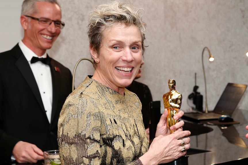 Frances McDormand smiles while holding her Oscar with both hands.