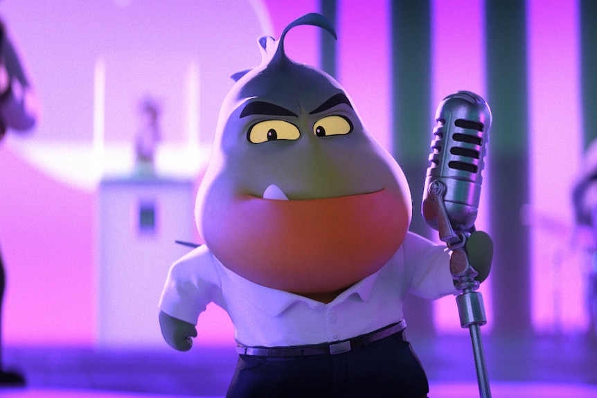 Animated green and orange piranha wears white shirt and black pants and wields a microphone on a pink-lit stage.
