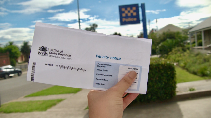 Hand holding a folded up piece of paper, police sign in the distance