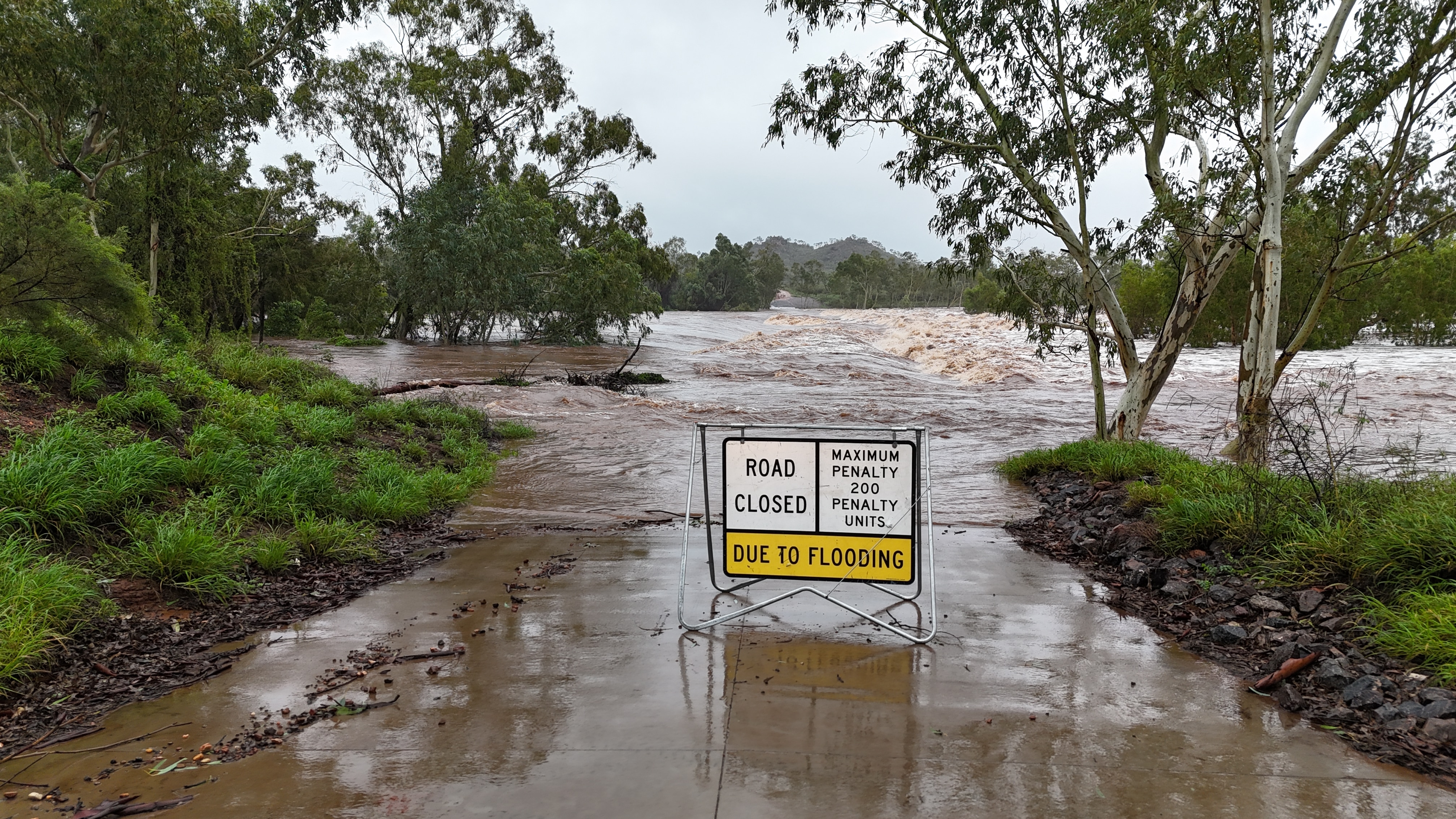 uma estrada fechada devido a um sinal de inundação em frente a uma estrada inundada