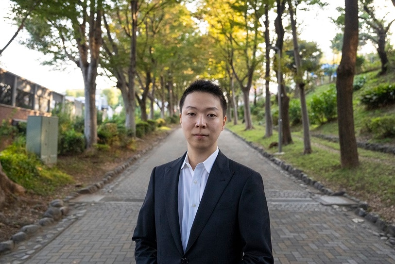 Medical student Yuzo Takeguchi standing on a pathway in a garden.