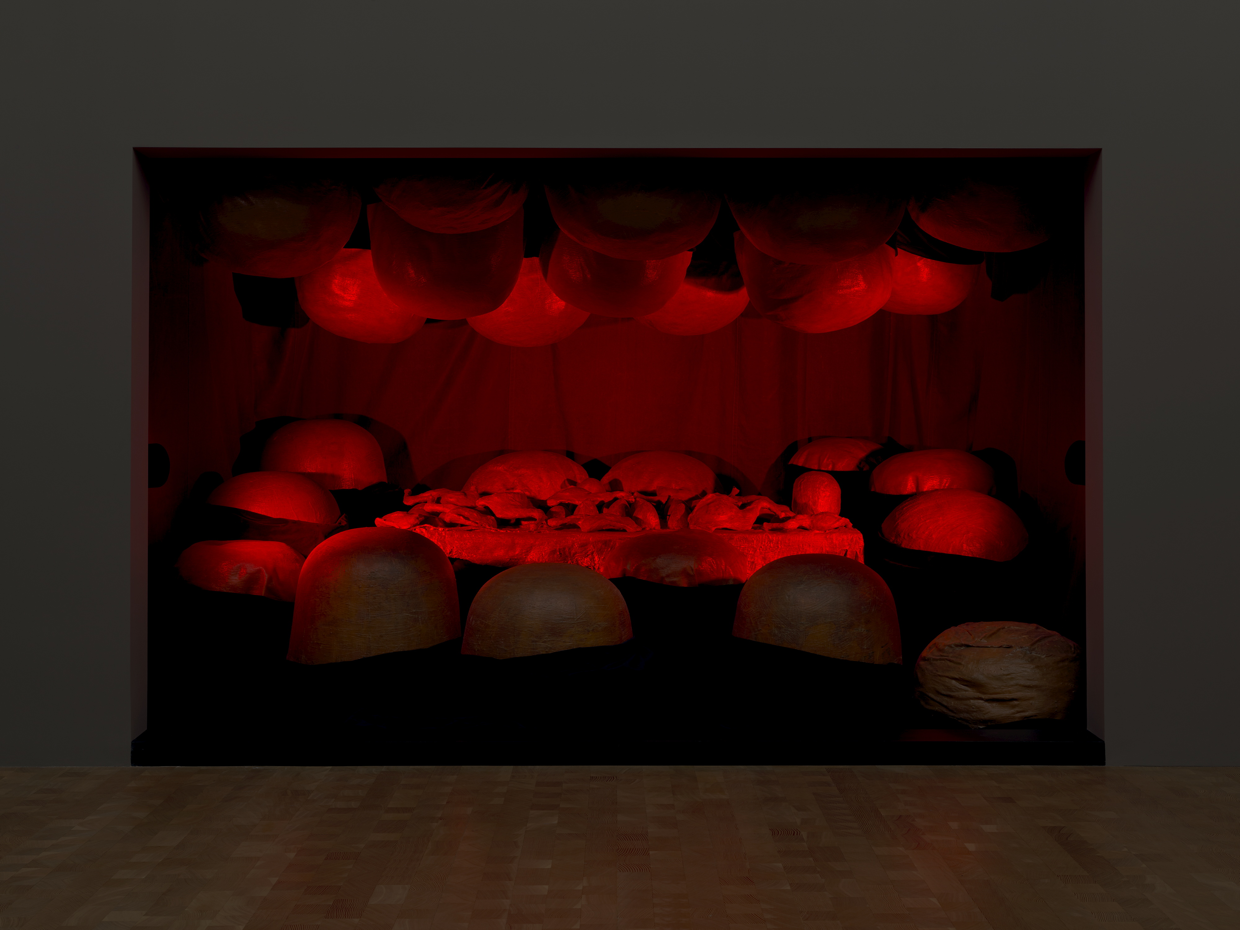 Installation art of red circle bubbles on roof and floor in red lit dark room. 