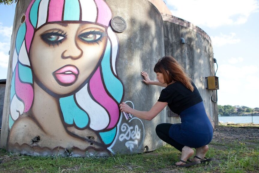 Street artist Deb at work on Sydney's Cockatoo Island as part of the Outpost street art festival.
