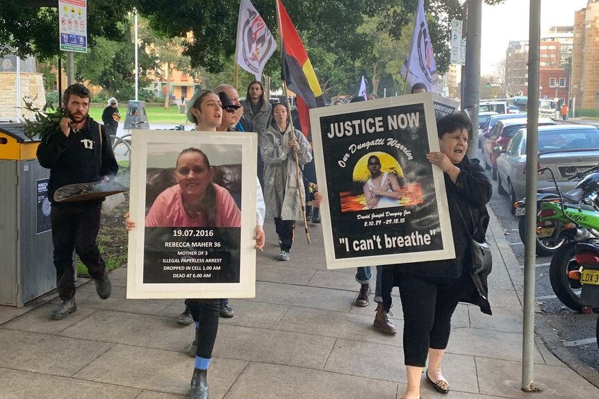 people marching in support of Rebecca Maher, carrying signs and Aboriginal flag