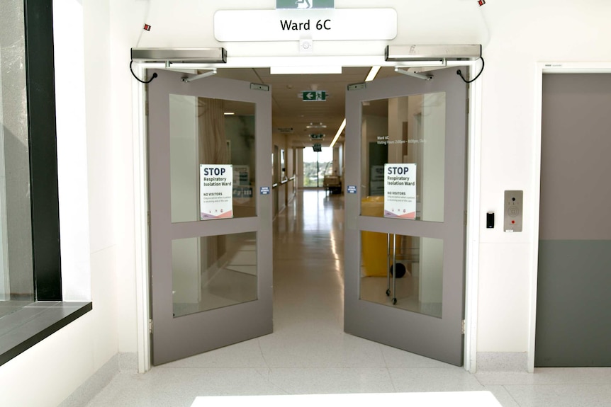 Double doors open to an empty hallway with the words "STOP" bold on a poster on the doors.