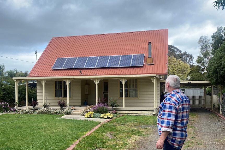 A man looking back on his home which has solar panels