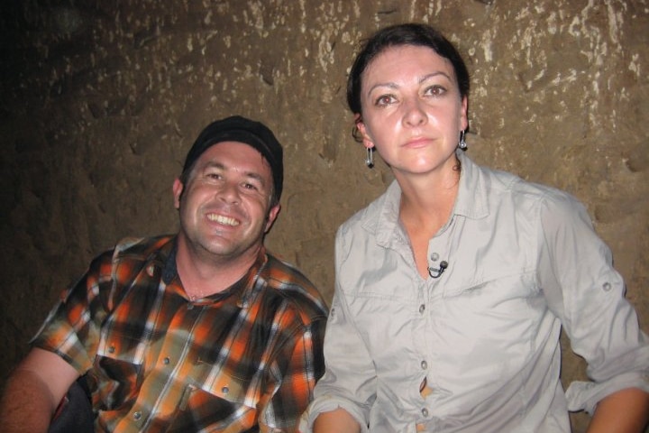A medium photo of a man smiling and a woman next to him inside an underground tunnel