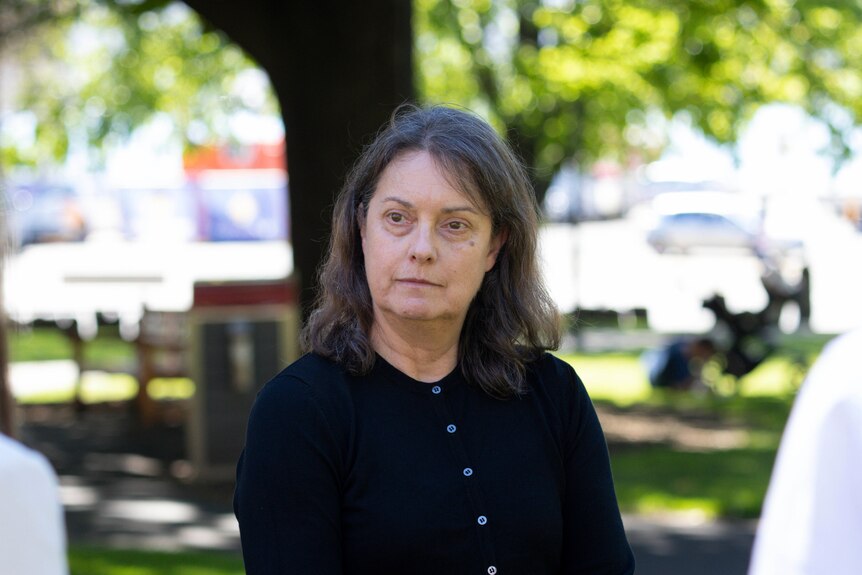 Jill Maxwell in front of a tree, wearing black, looking intently at a journalist behind the camera.