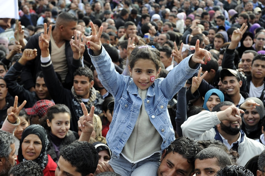 Girl gives peace sign as Tunisians mark uprising anniversary