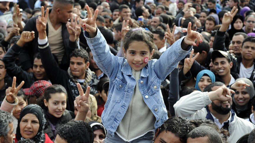 Girl gives peace sign as Tunisians mark uprising anniversary